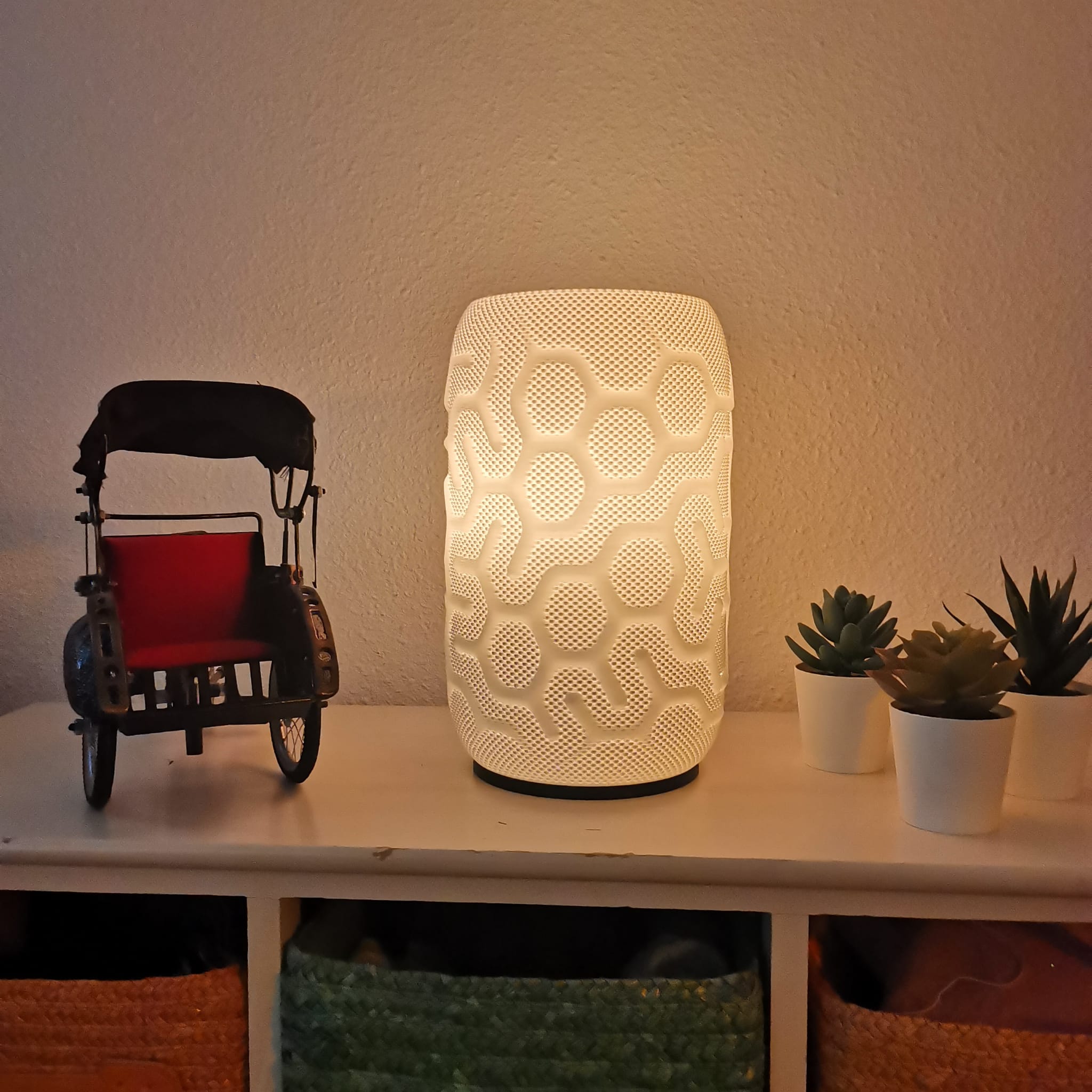 Decorative lamp with geometric pattern on a shelf with a toy and plants