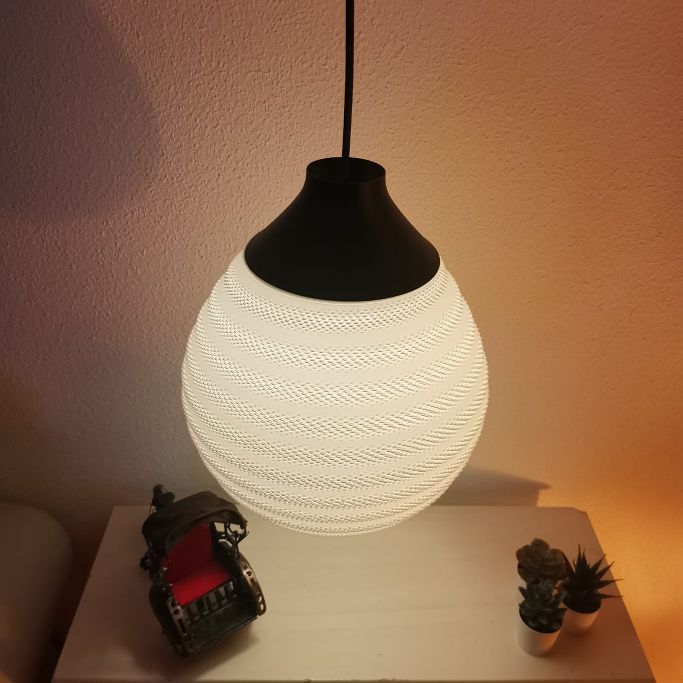 Textured spherical lamp with black top on a white surface, soft lighting