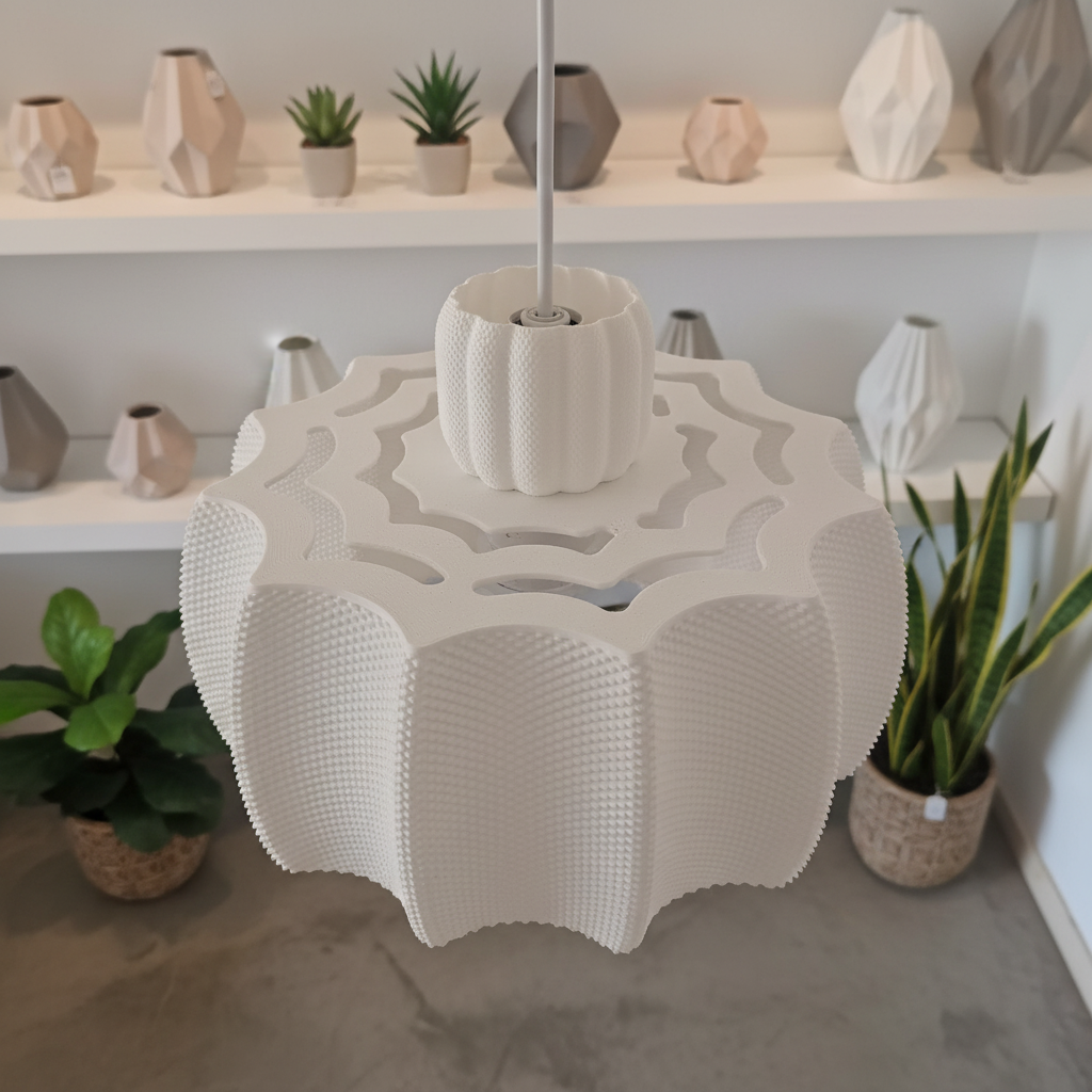 Close-up of a modern white pendant lamp with organic ridges and perforated details, shown in a minimalist interior.