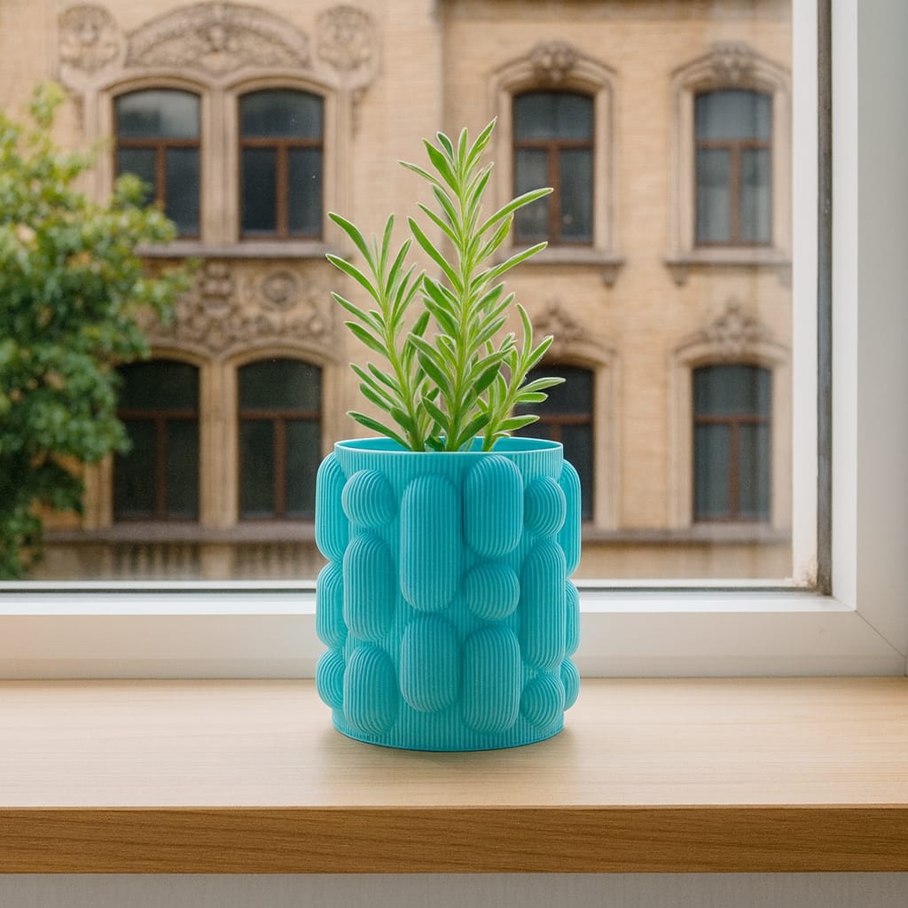 Blue textured planter with a plant on a windowsill in front of a building.