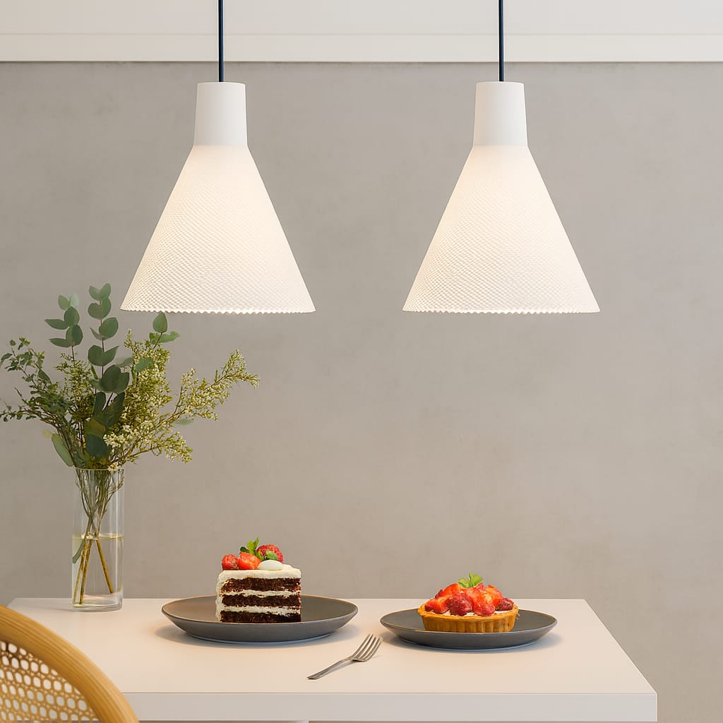 Two white pendant lights hanging above a table with desserts and a vase of flowers.