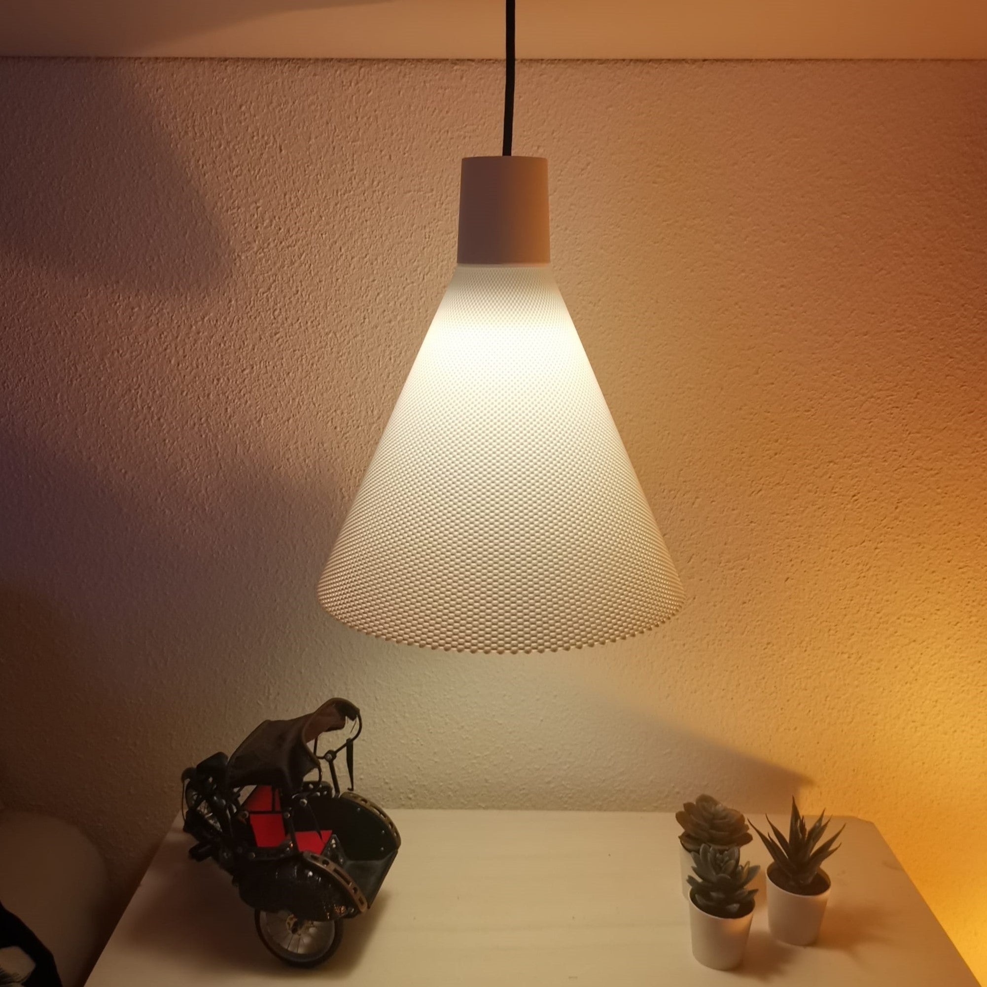 Modern pendant light casting a warm glow on a wall with decorative items below.