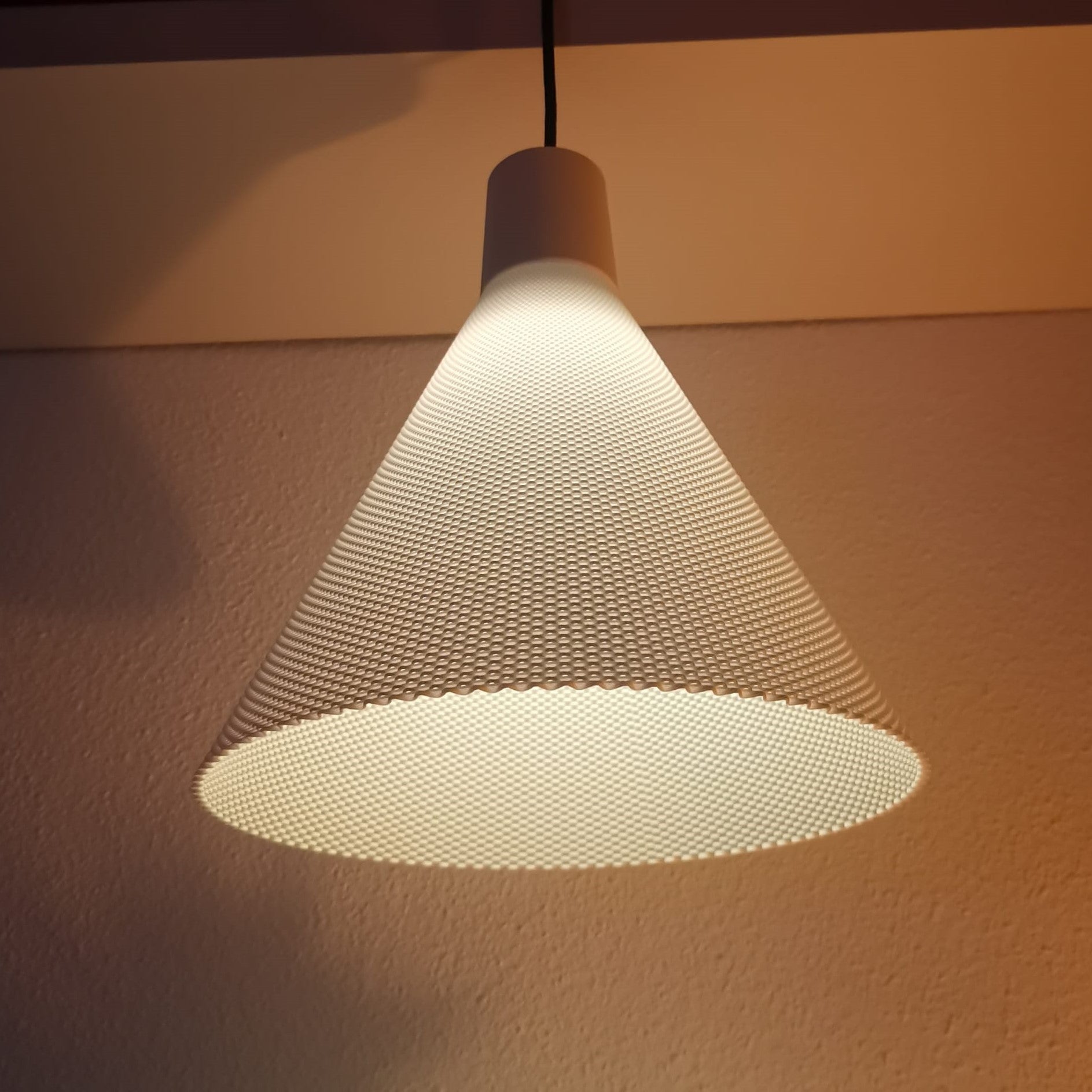 Textured cone-shaped lampshade casting a warm glow on a plain wall.
