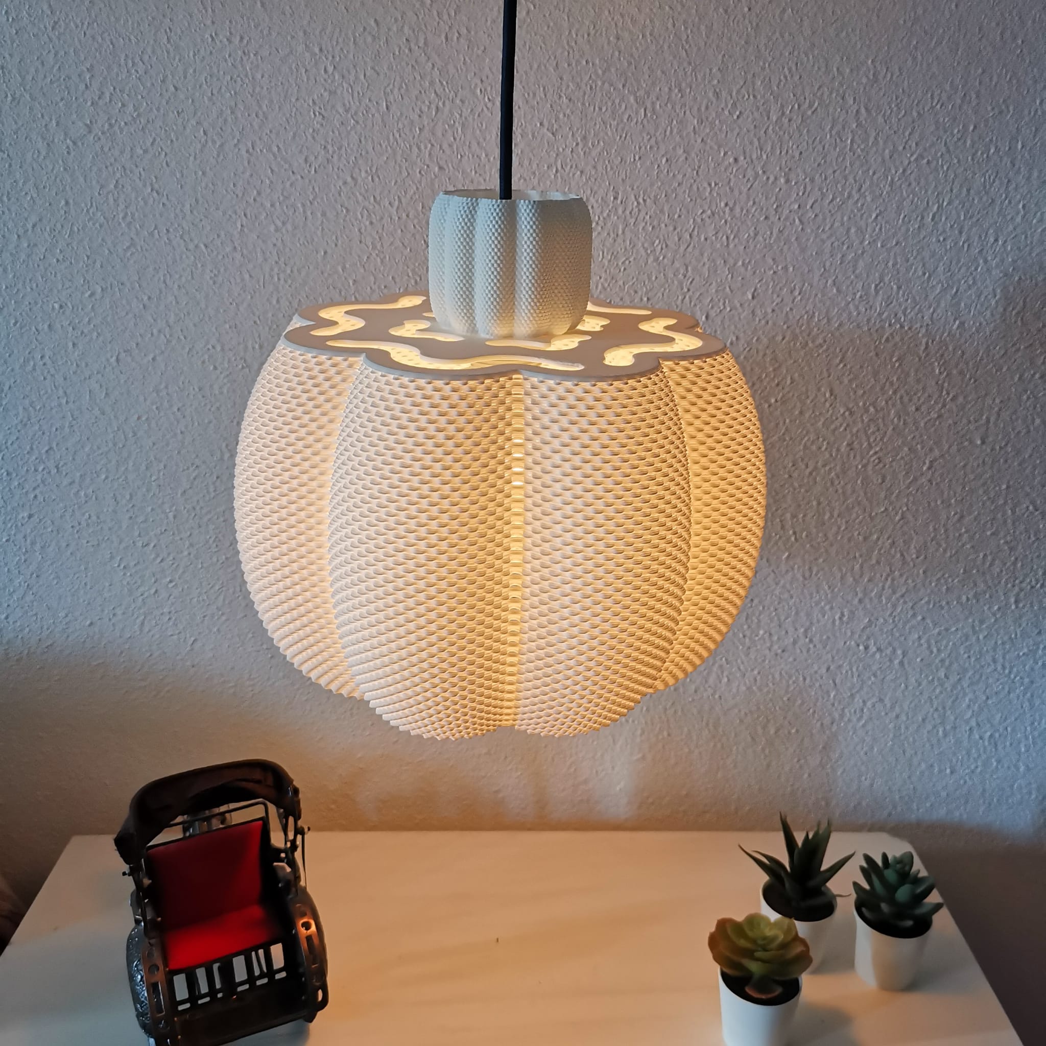 Round woven pendant light hanging above a table with decorative items.