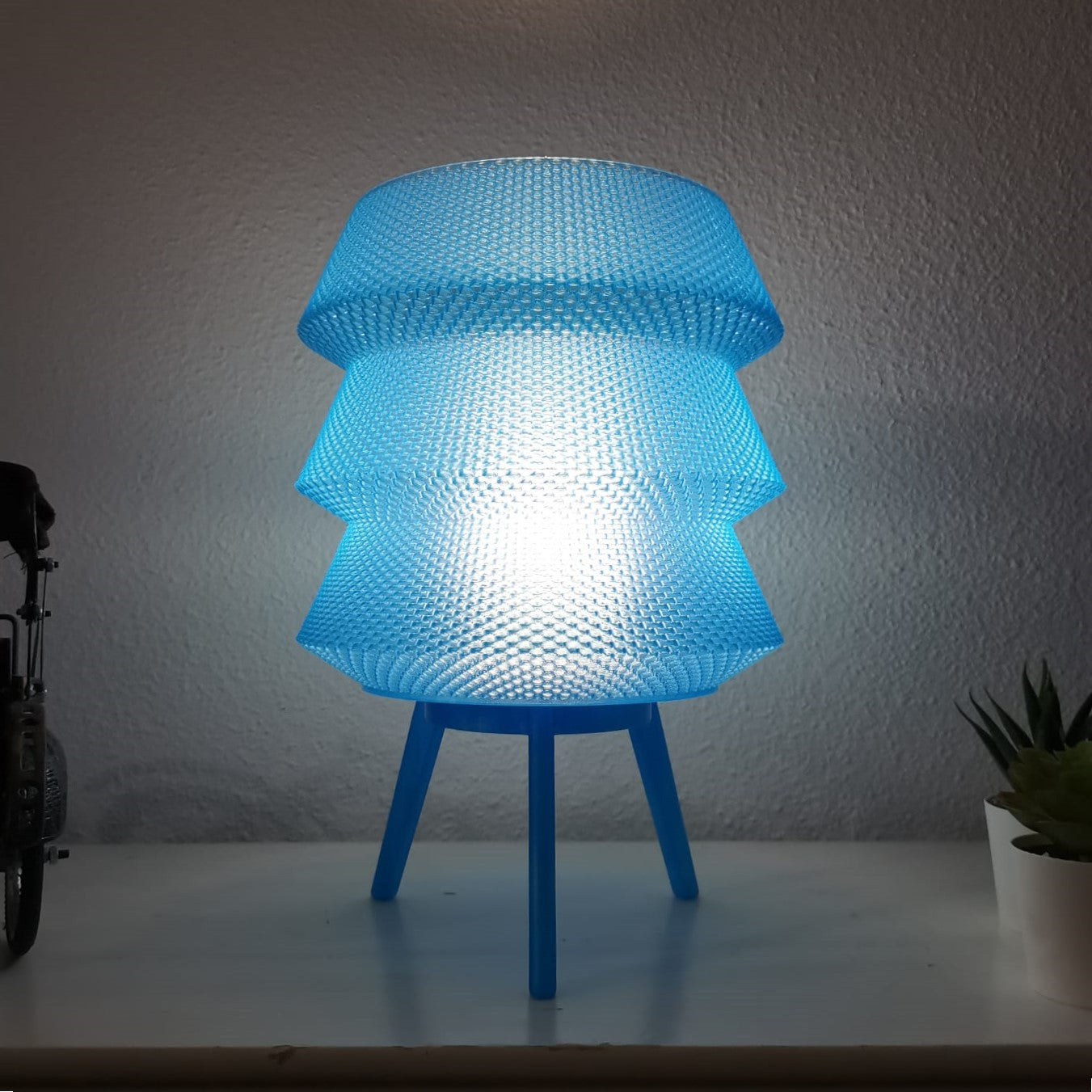 Blue textured lamp on a white surface with a light gray wall background