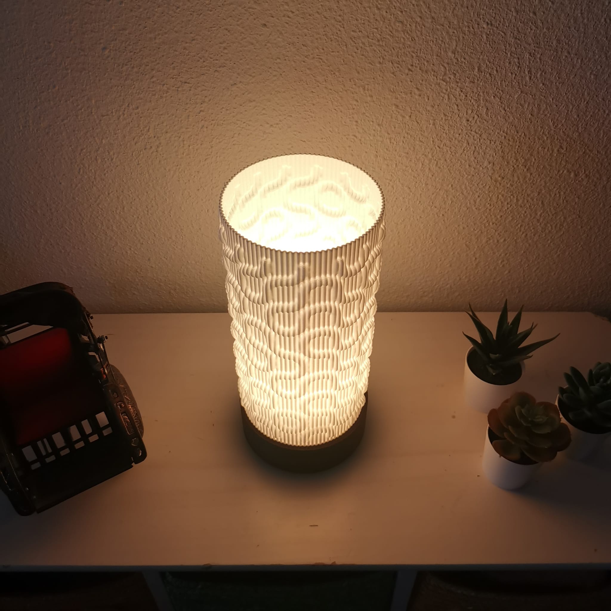Textured table lamp on a surface with plants and a basket in the background