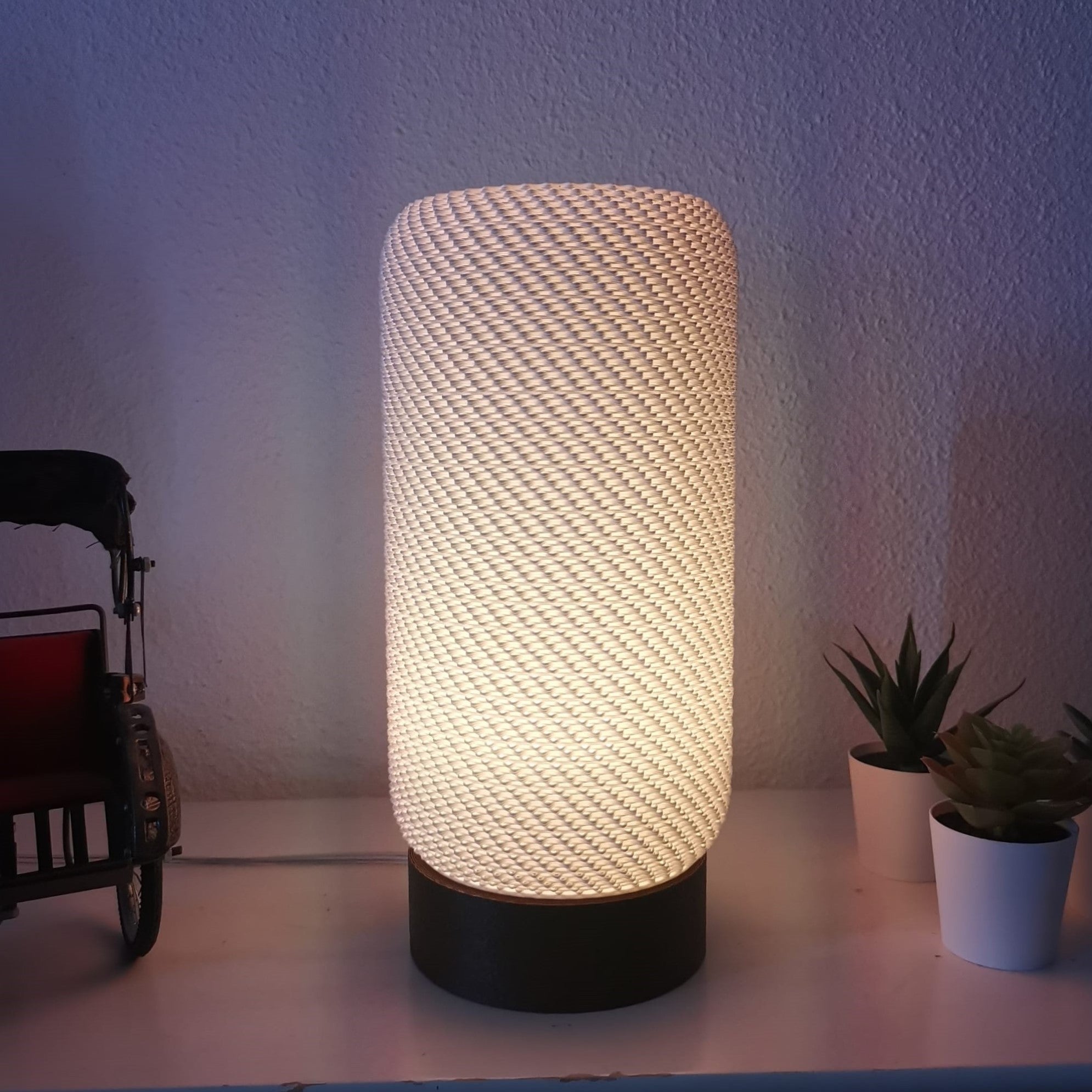 Textured table lamp on a surface with a toy and plants in the background