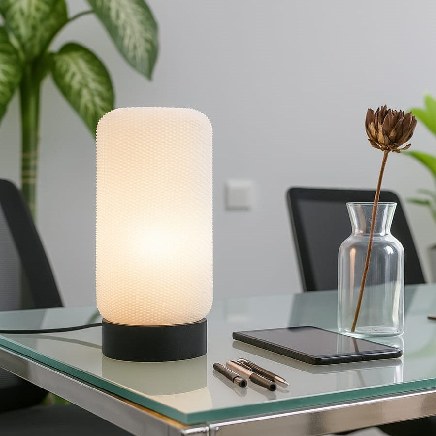 Table lamp on a desk with a phone, pen, and vase in a home office setting
