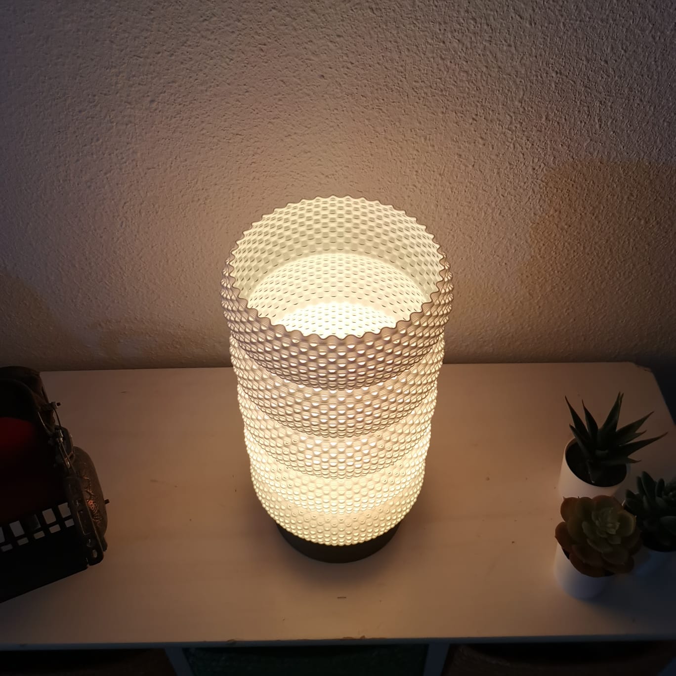 Decorative lamp with honeycomb pattern on a table with plants