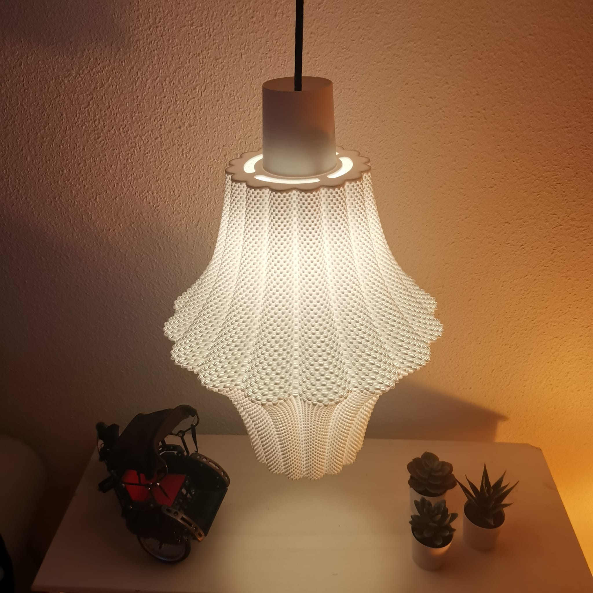 Decorative lamp with a textured design on a table with plants and a small object.