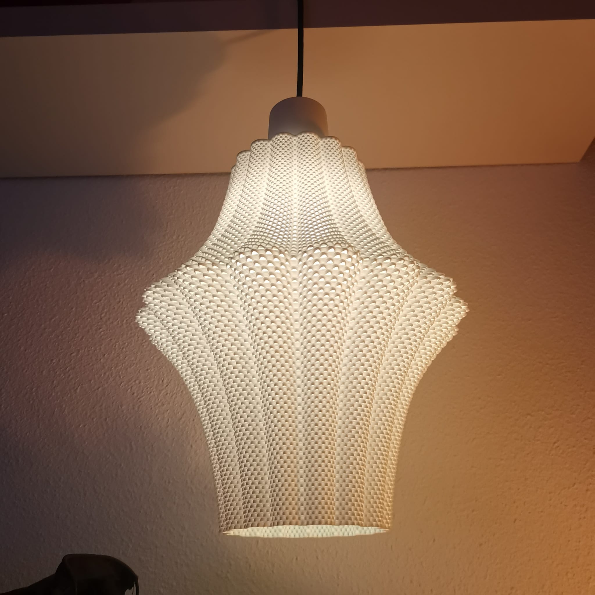 Textured lampshade hanging against a plain wall