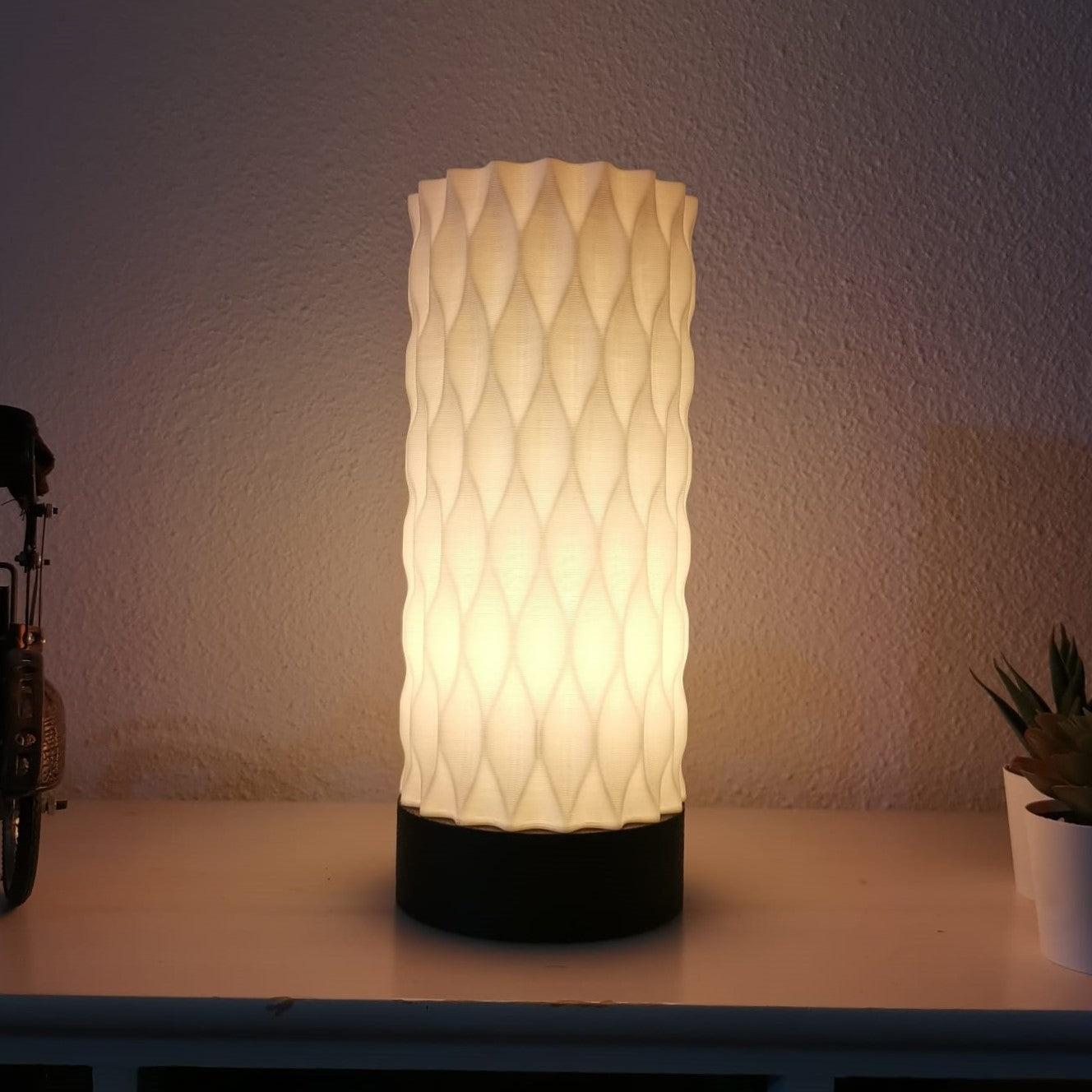 Decorative lamp with textured design on a surface against a neutral wall.
