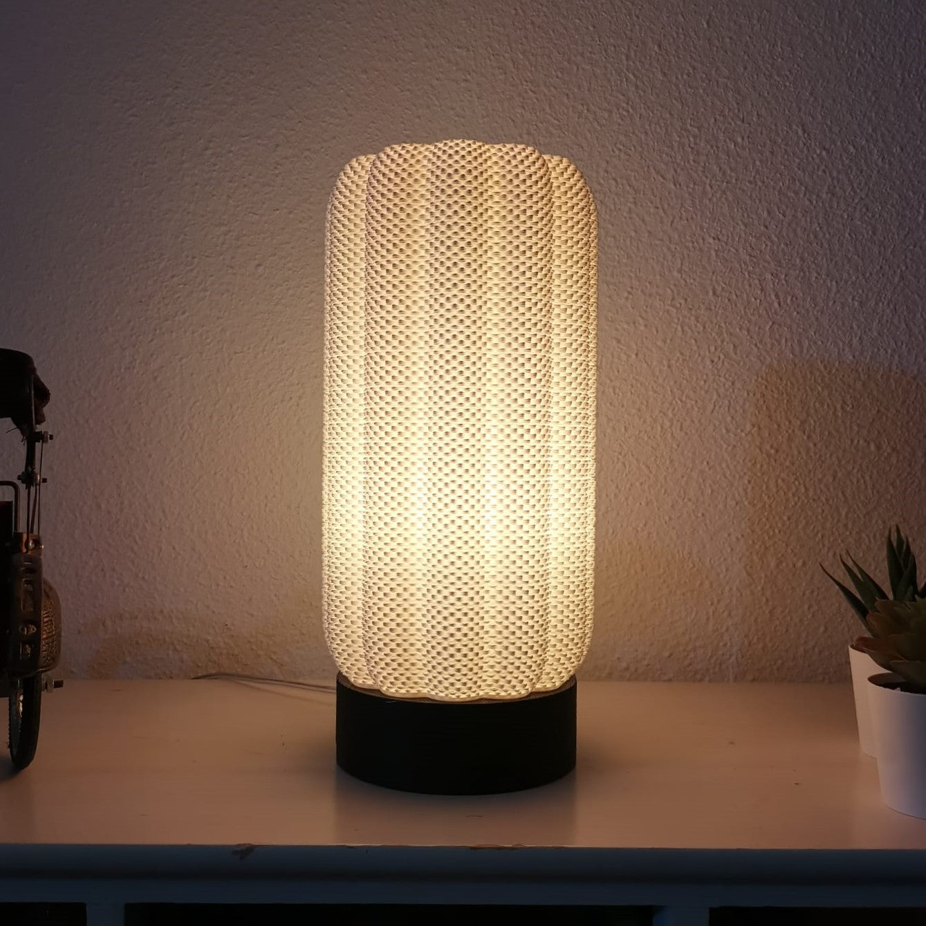 Textured table lamp on a surface with a soft glow against a neutral background