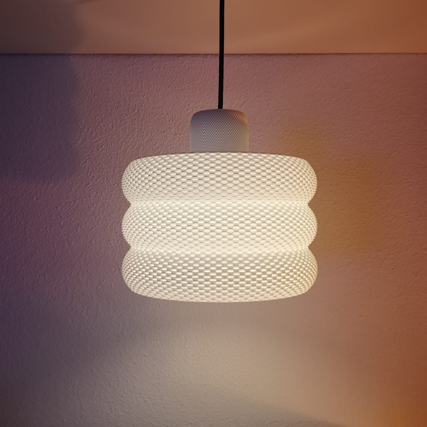 Textured pendant light hanging against a neutral wall