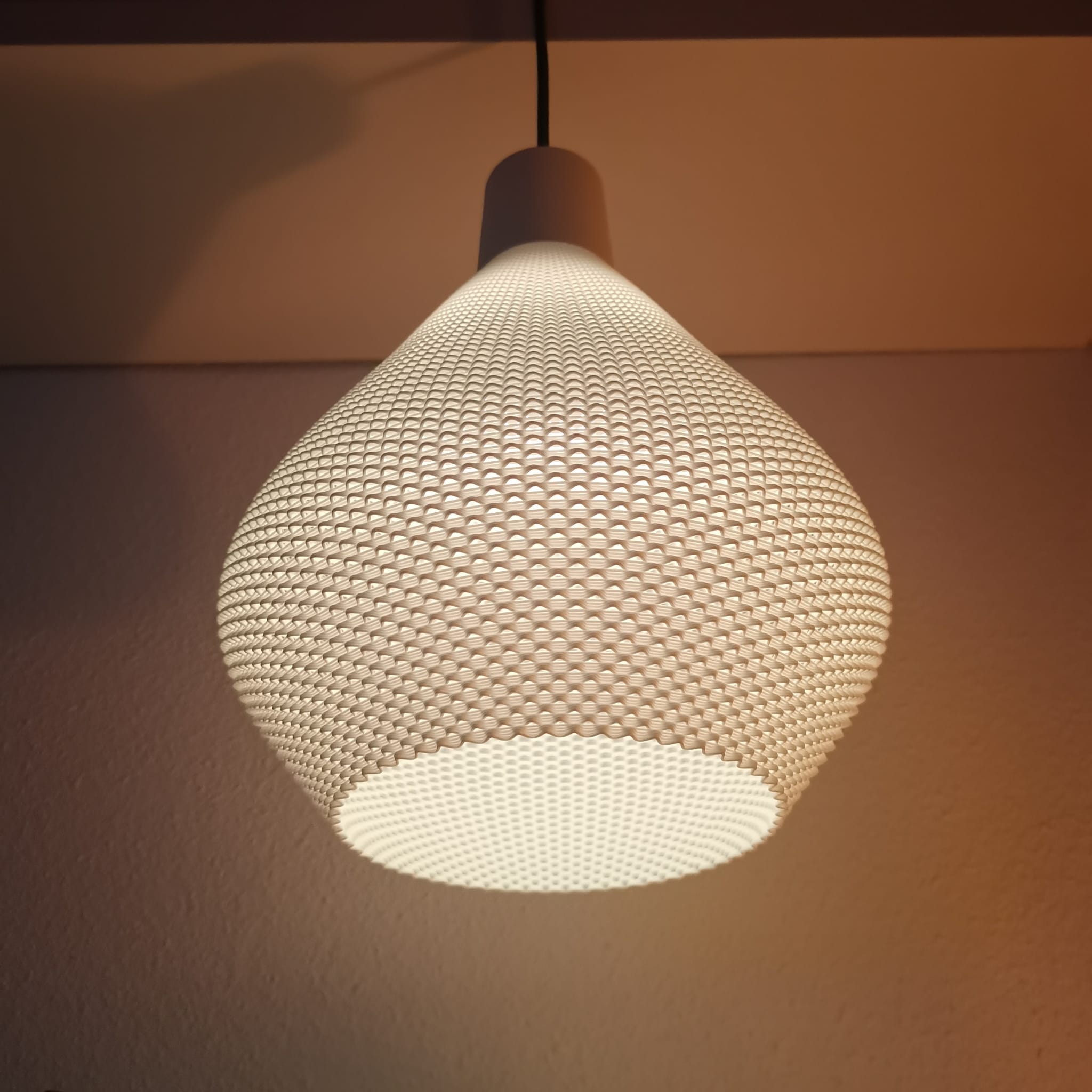 Textured pendant light fixture casting a warm glow on a plain wall.