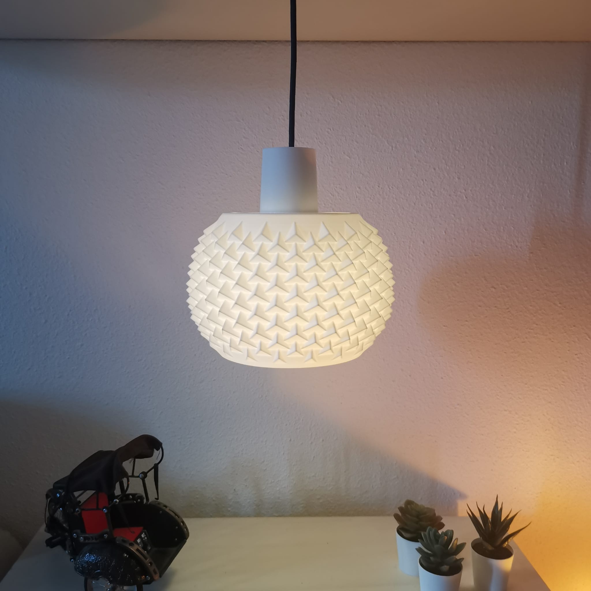 White woven pendant light on a white wall with decorative items below