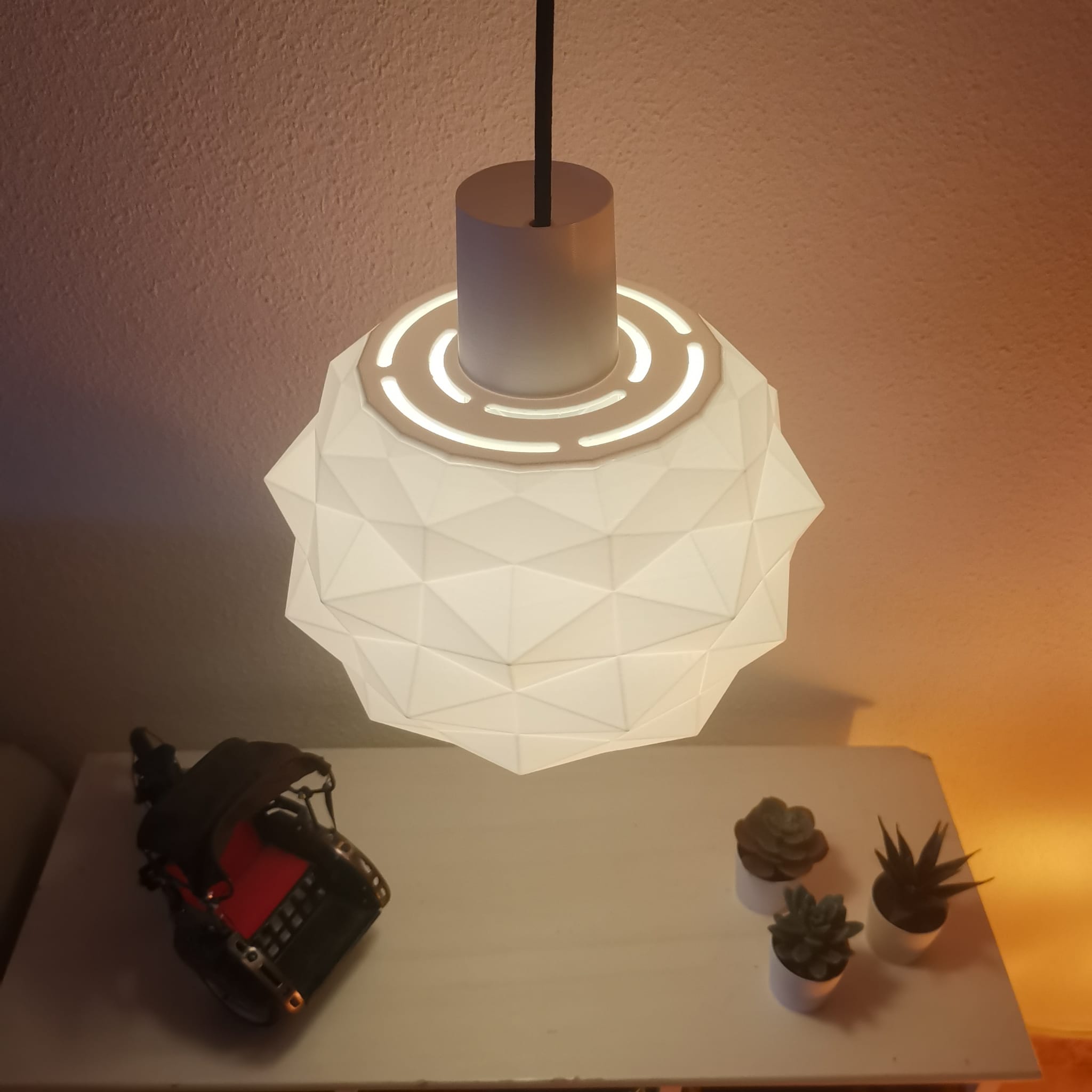 Geometric pendant light on a table with plants.
