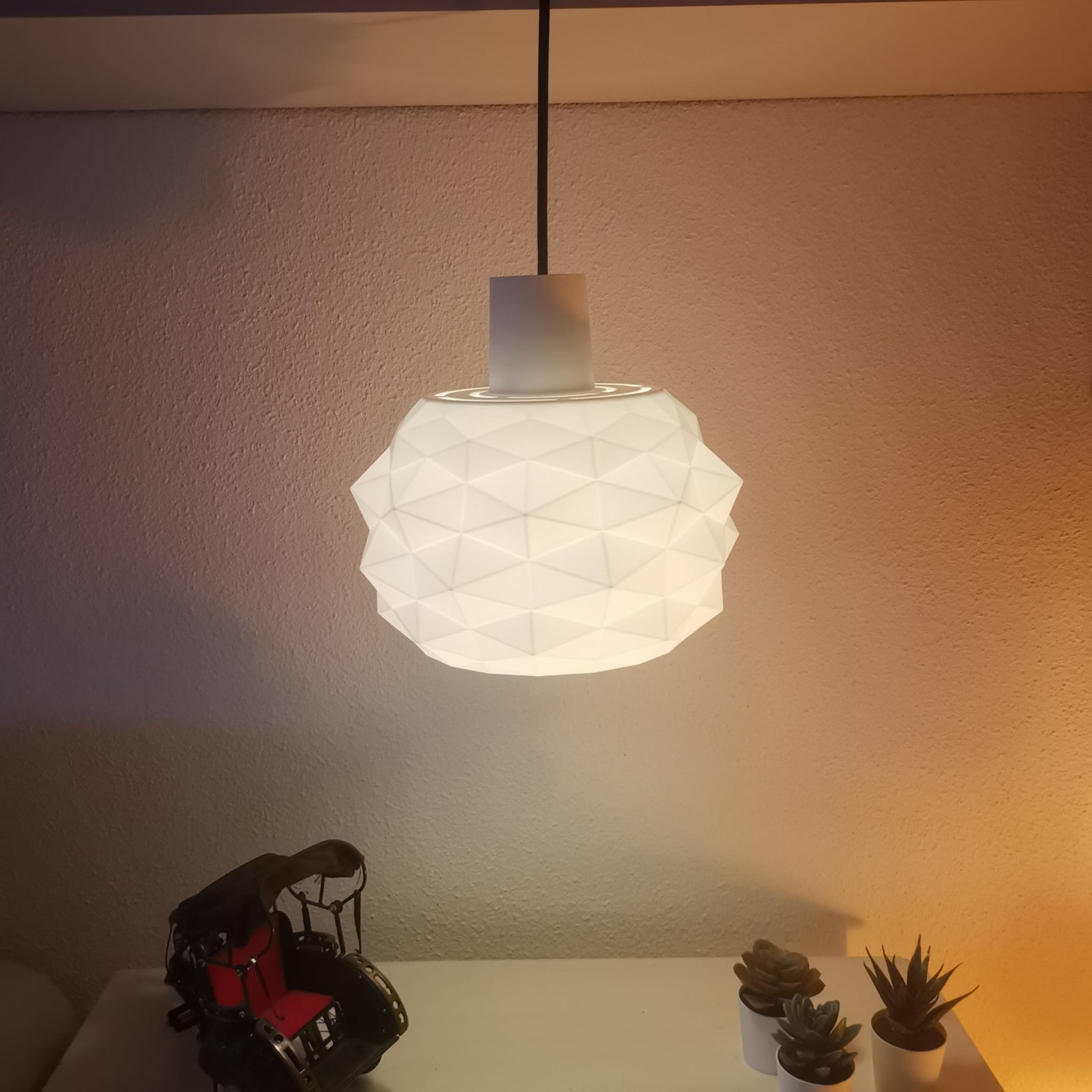 White textured pendant light hanging above a table with decorative items.