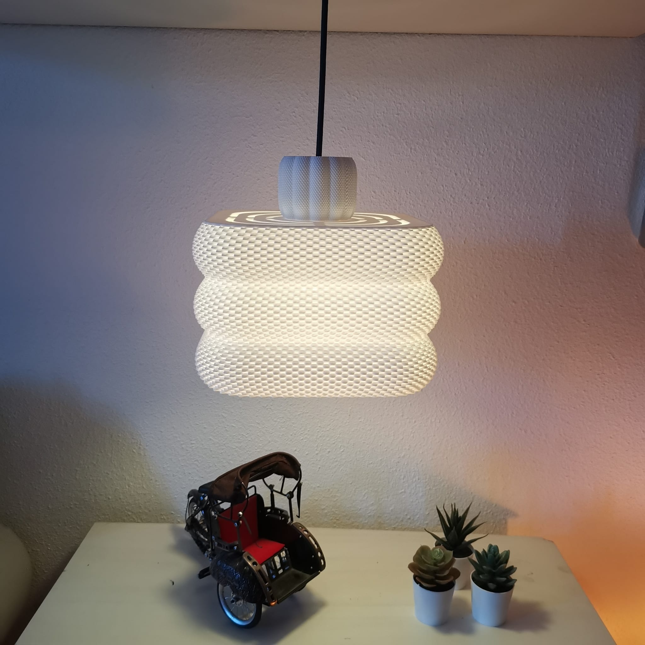 Pendant light fixture on a white surface with decorative items