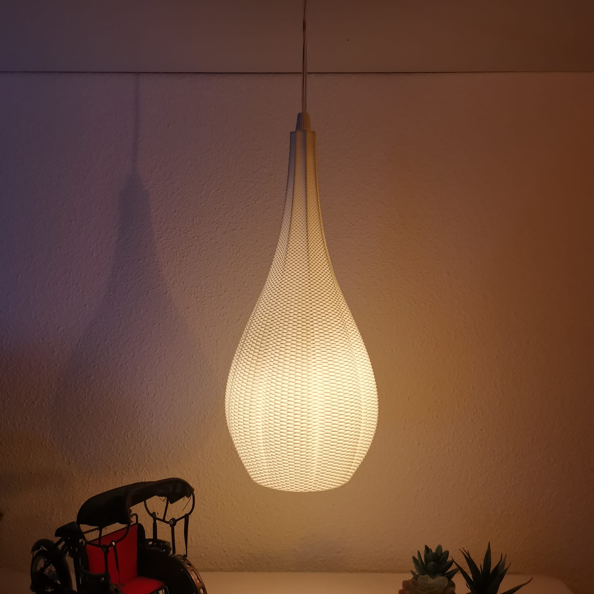 Teardrop hanglamp die warm licht verspreidt in een minimalistische setting.