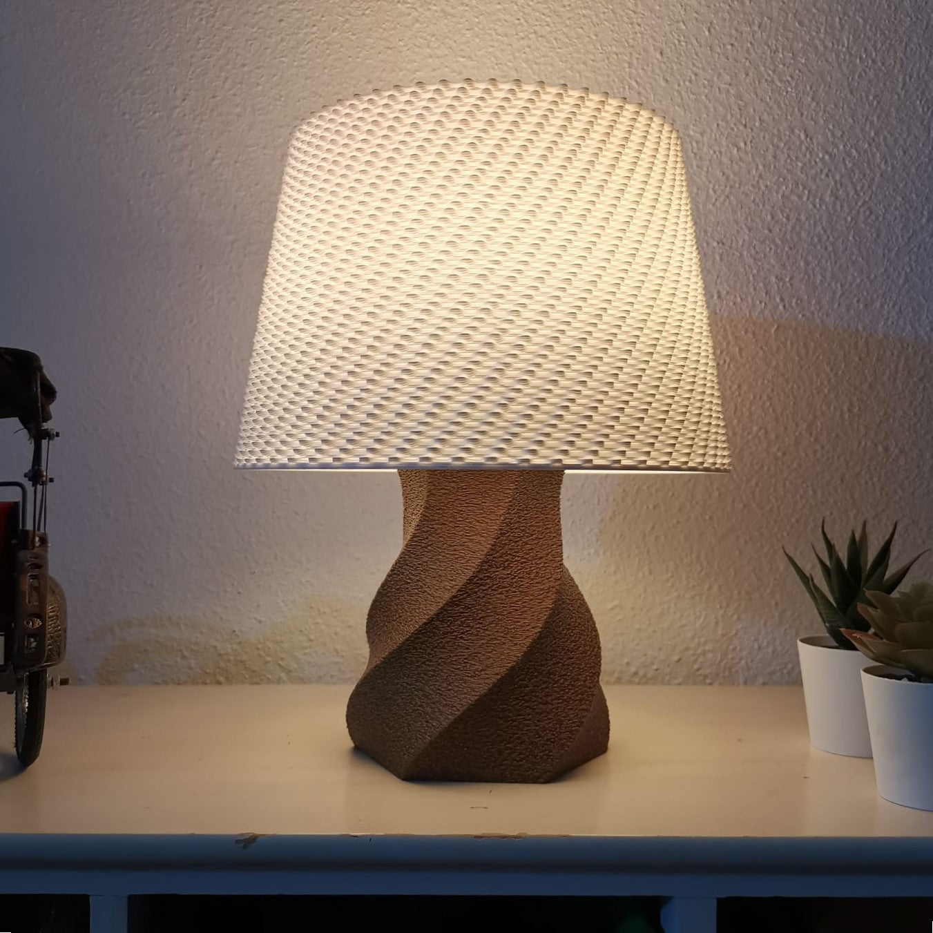 Table lamp with textured shade on a surface against a neutral wall