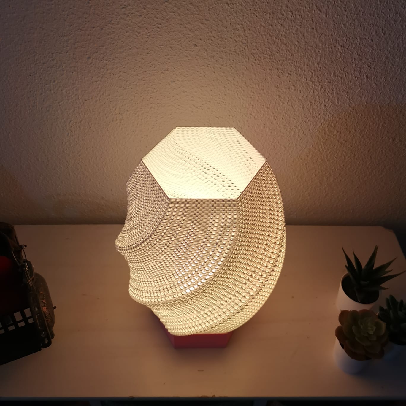 Decorative lamp shaped like a face on a table with plants in the background
