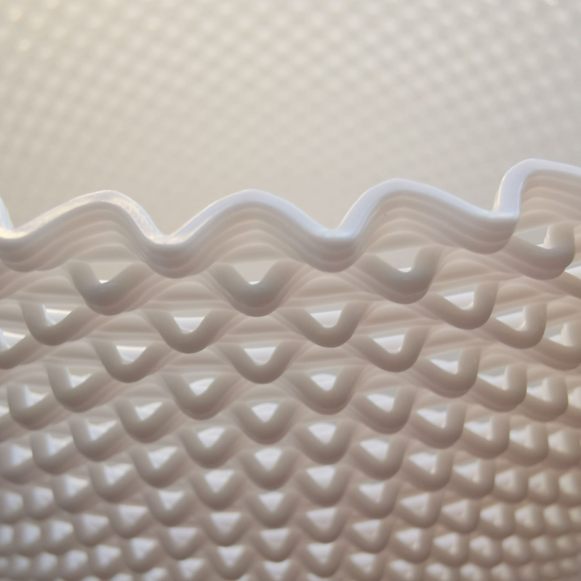Close-up of a textured white table lamp with wavy rim on a light beige background