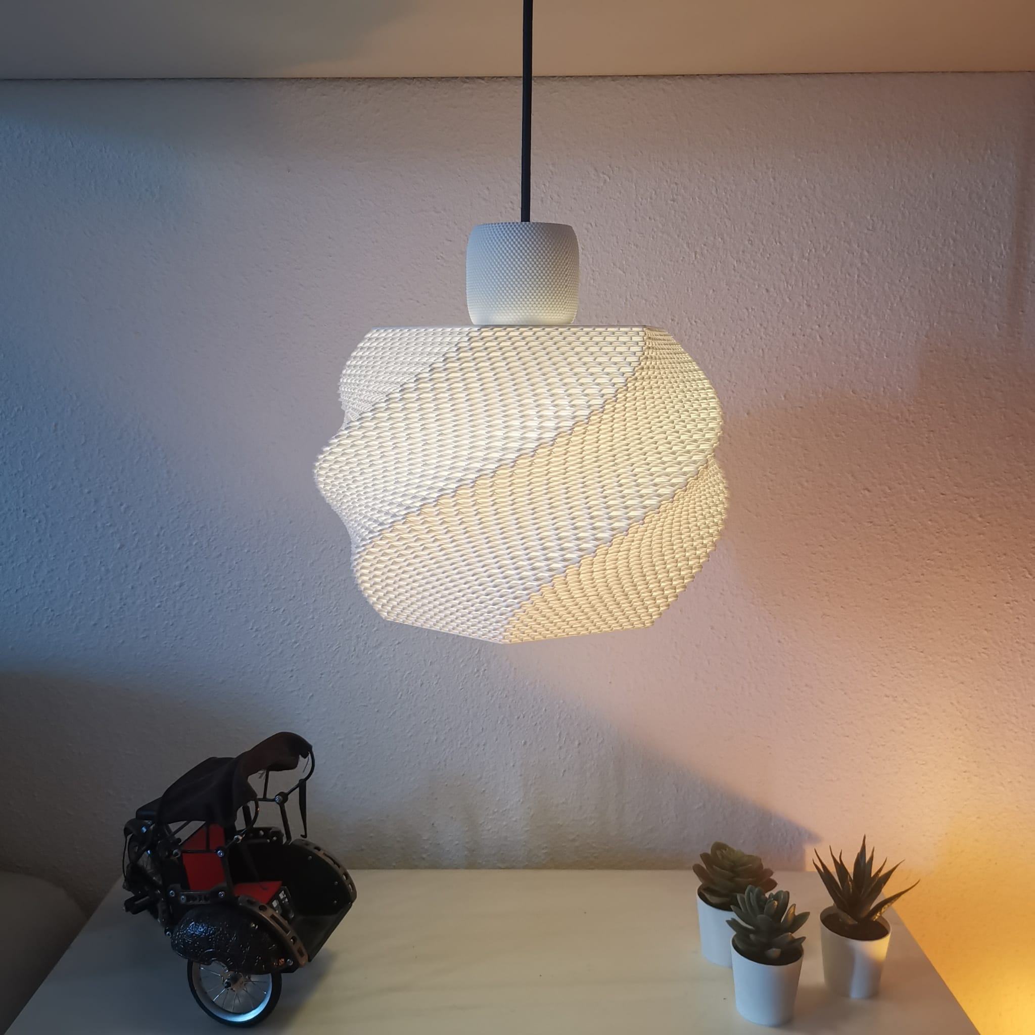 Modern pendant light fixture on a white wall with decorative items below.