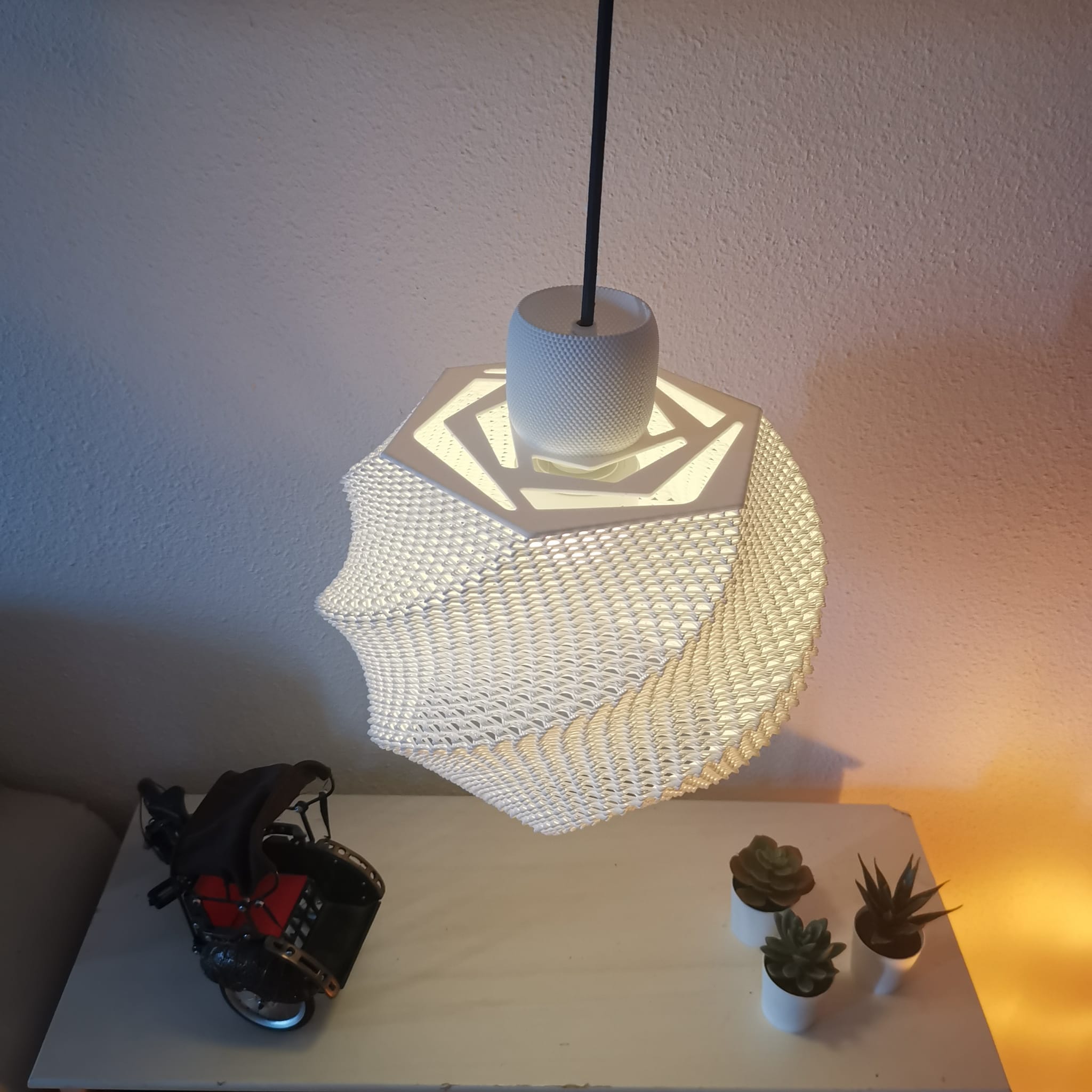 Modern pendant light fixture on a table with decorative plants and a toy car.