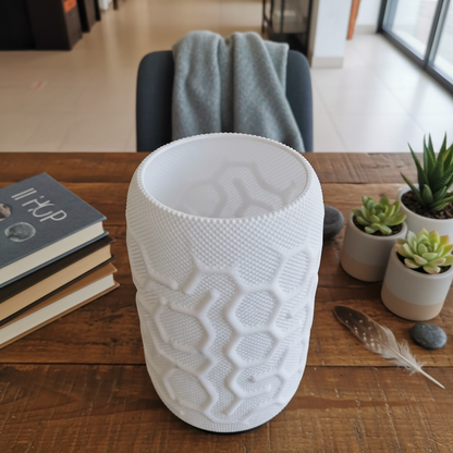 White textured vase on a wooden table with books and plants in the background