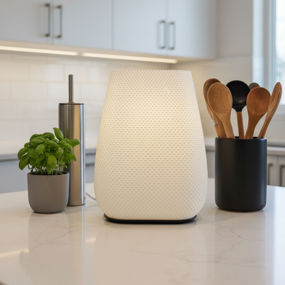 White textured lamp on a kitchen counter with a plant and utensils in the background