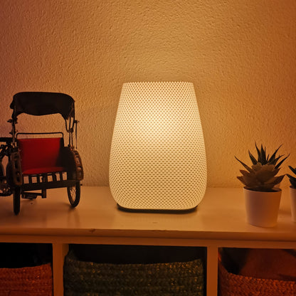 Textured warm glow lamp on shelf beside miniature rickshaw and small potted plant — cozy ambient home lighting.