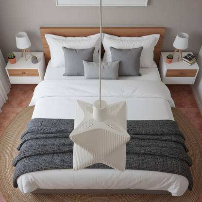 Sculptural white pendant lamp centered above a neatly styled double bed in a minimalist bedroom.