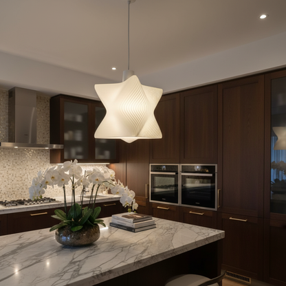 Sculptural white pendant lamp with flowing ribbed design hanging above a marble kitchen island in a modern dark-wood kitchen.