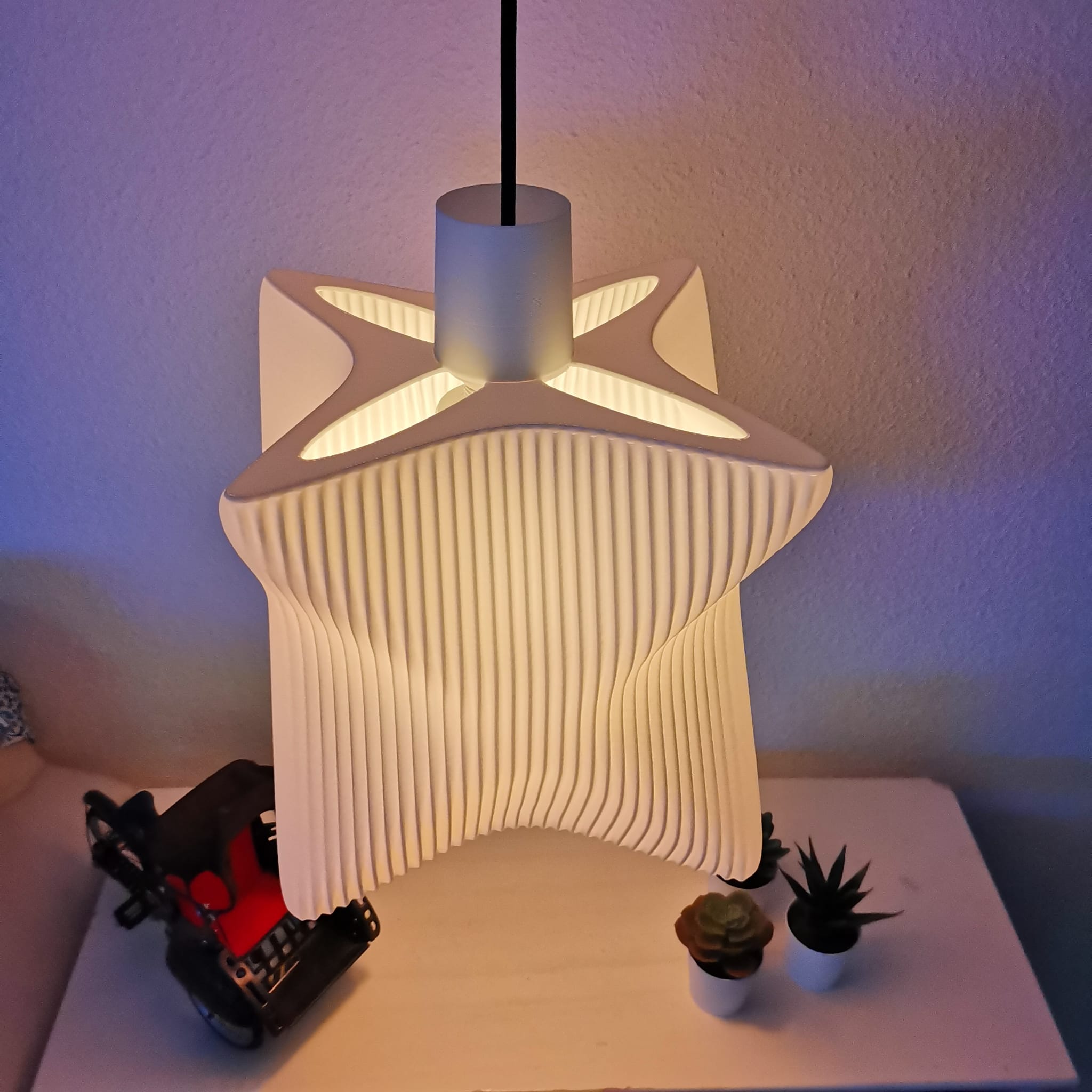 Modern pendant light with ribbed design on a white surface with decorative items.