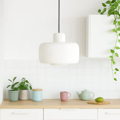 Modern kitchen with a white pendant light, wooden countertop, and decorative items.
