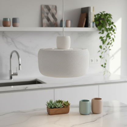 Modern white pendant lamp suspended above a minimalist kitchen with marble countertop and decorative plants.