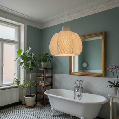 White sculptural pendant light hanging above a bathtub in a modern bathroom with glossy green tiles and brass fixtures.