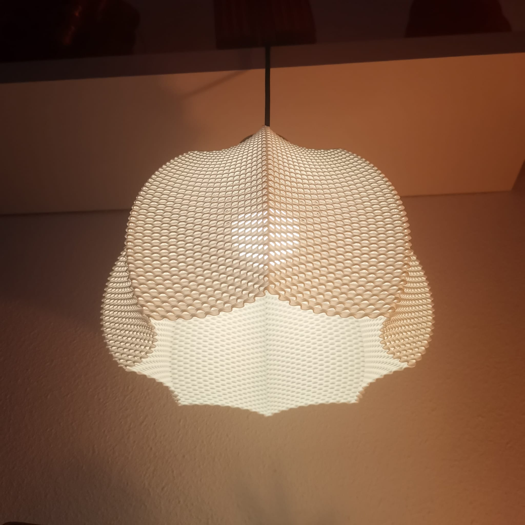 Textured pendant light fixture casting a shadow on a wall.