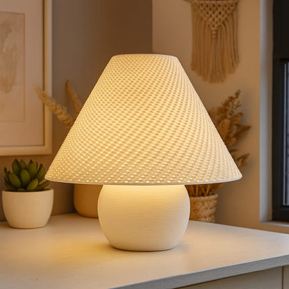 White textured table lamp on a surface with decorative items in the background