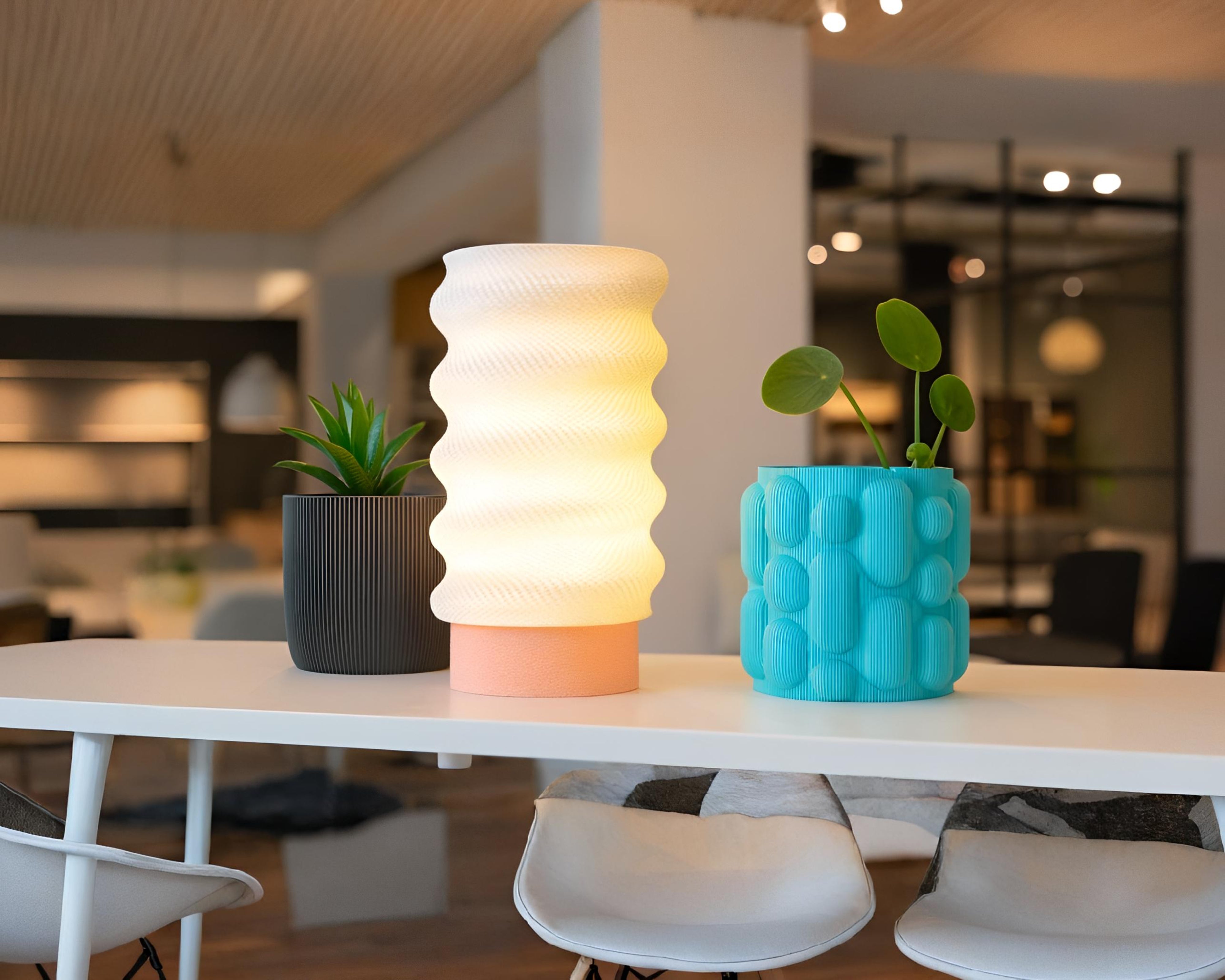 Two textured vases on a table with plants in the background
