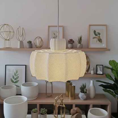 White designer pendant lamp with layered shade casting soft light in a styled living room with shelves and plants.