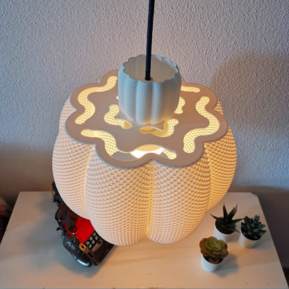 Decorative lamp with wavy design on a white surface with small plants
