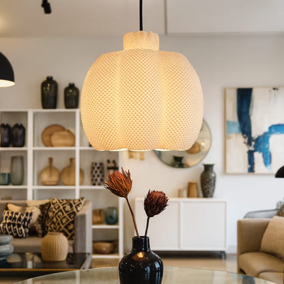 Textured pendant light in a living room setting with decor elements.