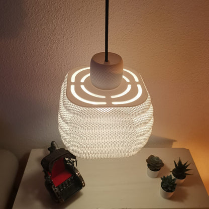Textured pendant light on a table with small plants and a toy car.