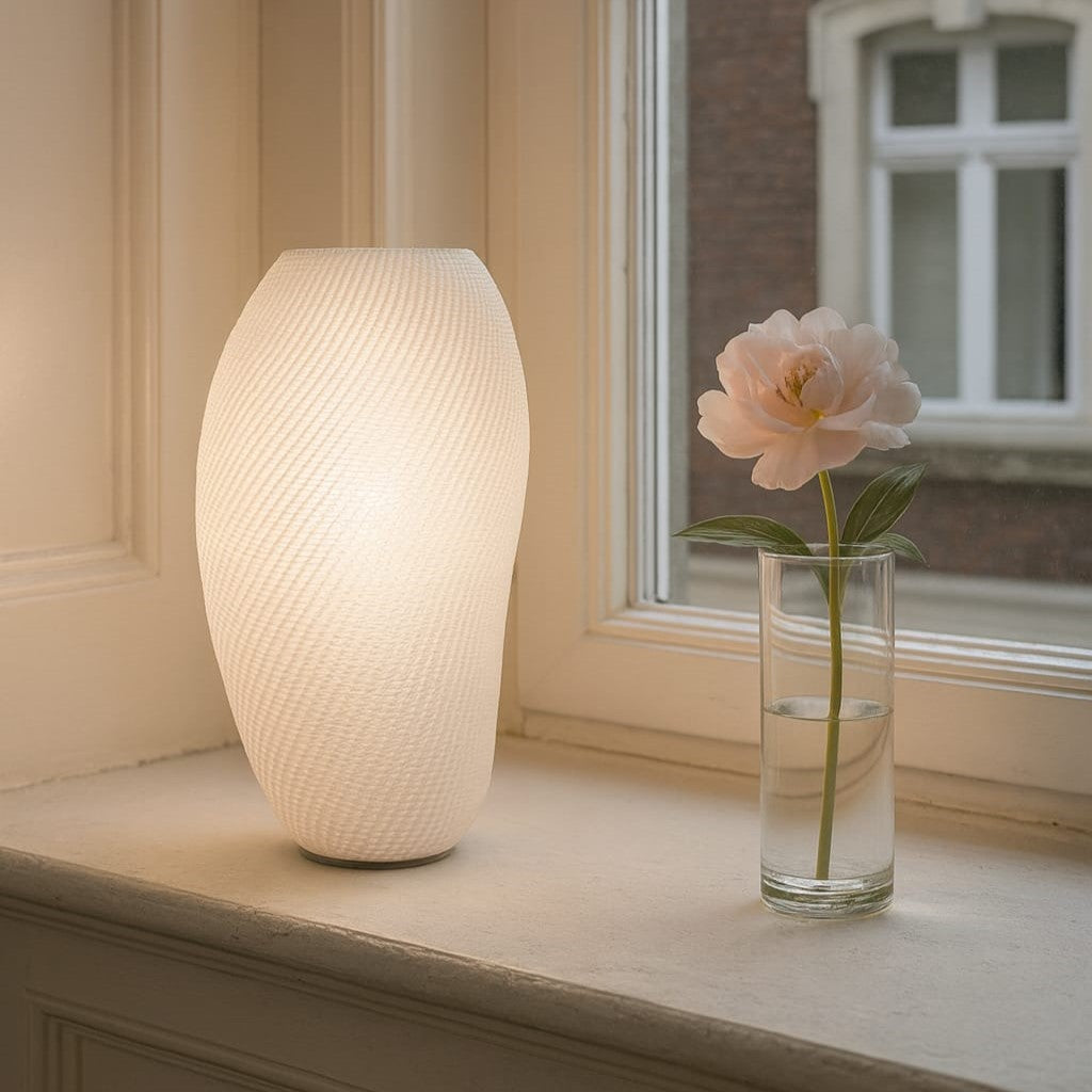 Eclipse Table Lamp glowing softly on a wooden nightstand, showcasing its sculptural 3D-printed design