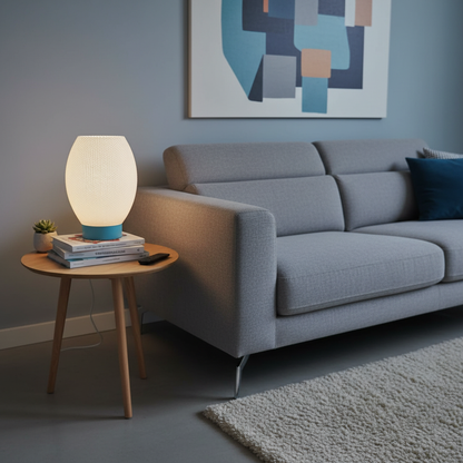 Modern living room with a gray sofa, side table with a lamp, and abstract art on the wall.