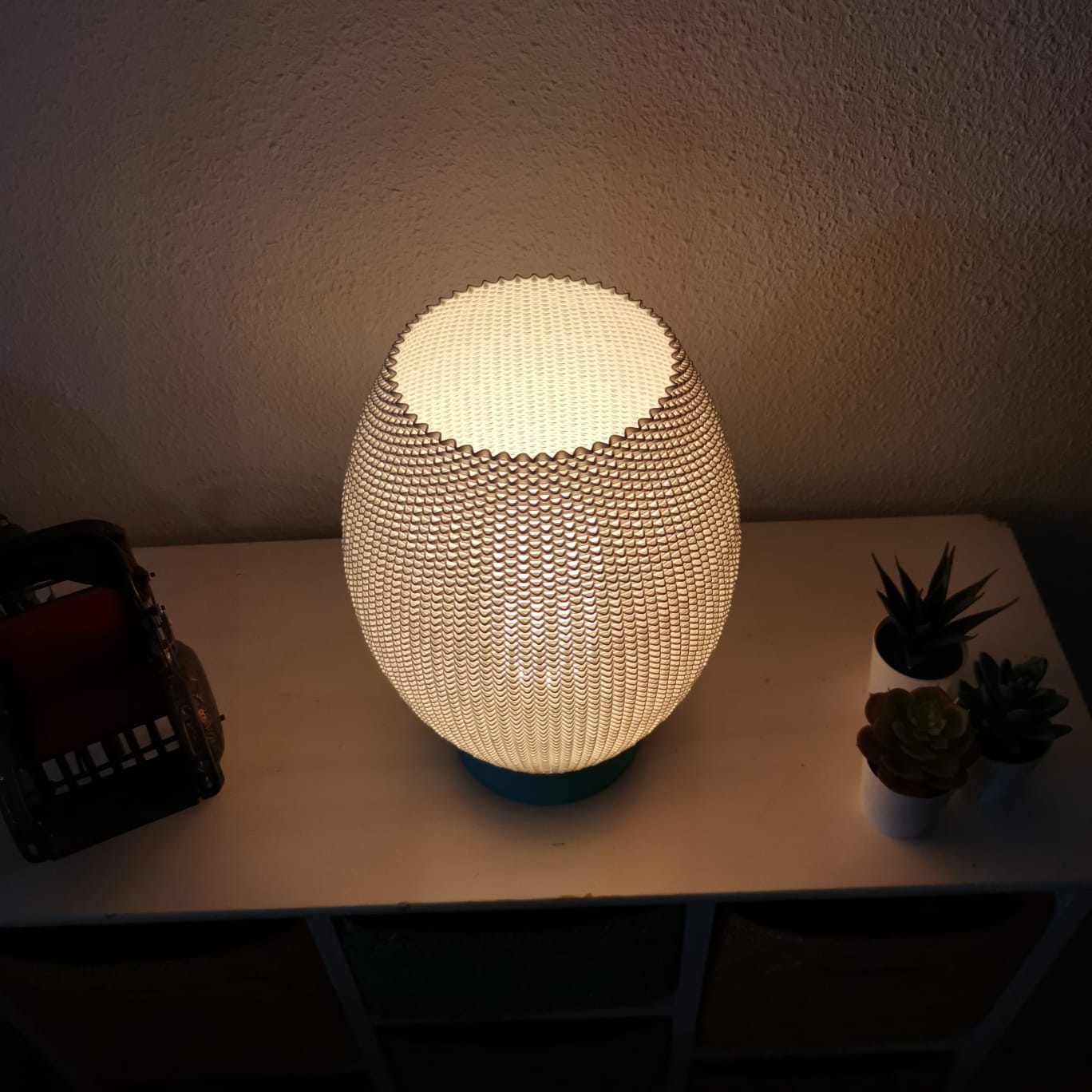 Textured table lamp on a surface with plants in the background