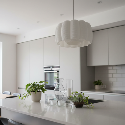 A white, sculptural pendant lamp with a ribbed texture hanging above a kitchen island in a sleek, minimalist kitchen with light cabinetry.