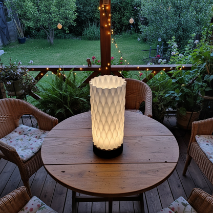 Outdoor setting with a wooden table and wicker chairs, featuring a lit decorative vase.